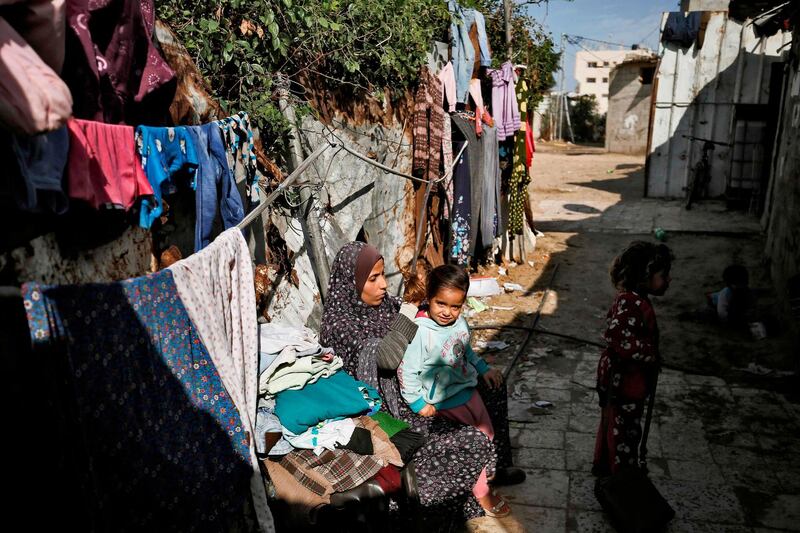 A Palestinian woman combs her daughter's hair as they sit outside their home in Gaza City.  AFP