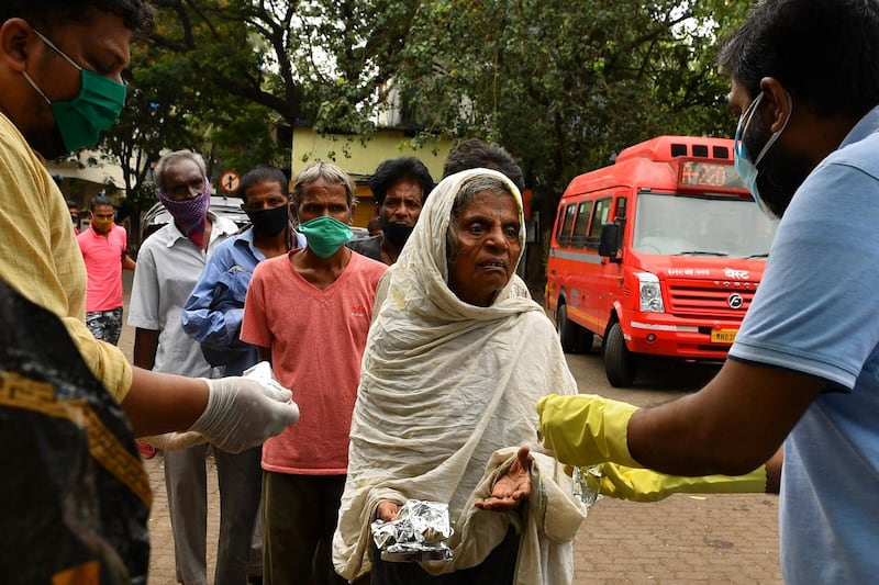 Ruben Mascarenhas, left, and Rakesh Singh, right, the co-founders of the non-profit Khaana Chahiye Foundation, distribute food to the needy outside a railway station in Mumbai. AFP