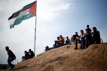 Palestinians sit near the Israeli-Gaza border fence east of Gaza City on March 29, 2019. Reuters