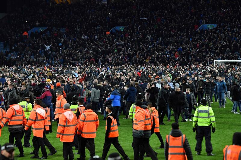 Police officers and stewards line the pitch as Aston Villa fans celebrate on the pitch. AFP