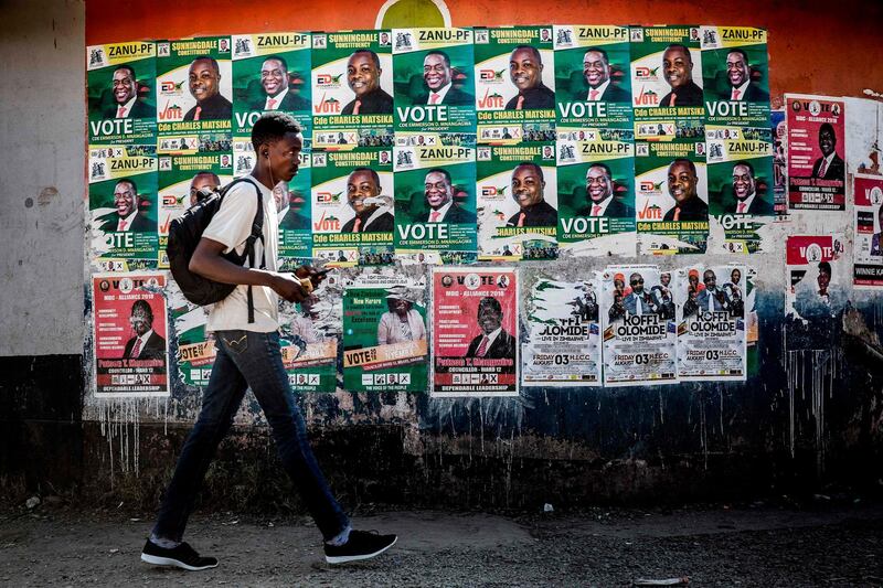 A man walks in front of electoral posters in a market at the suburb of Mbare in Zimbabwe's capital Harare on July 27, 2018, prior to the upcoming July 30, presidential election.  Mbare is a high-density suburb and one of the poorest areas of Harare and was known for being a former president Robert Mugabe's stronghold. The former president was ousted in November 2017, and his successor Emmerson Mnangagwa has promised a free vote, inviting back previously banned observers in an effort to show a renewed commitment to democracy. / AFP / Luis TATO

