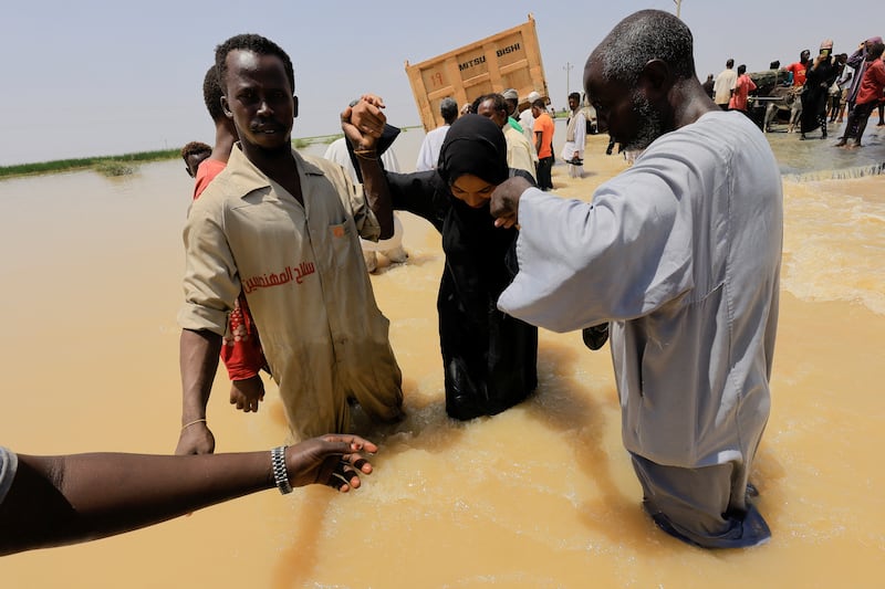 People wade through knee-deep water in the flooded district of Al Managil in Sudan. Reuters