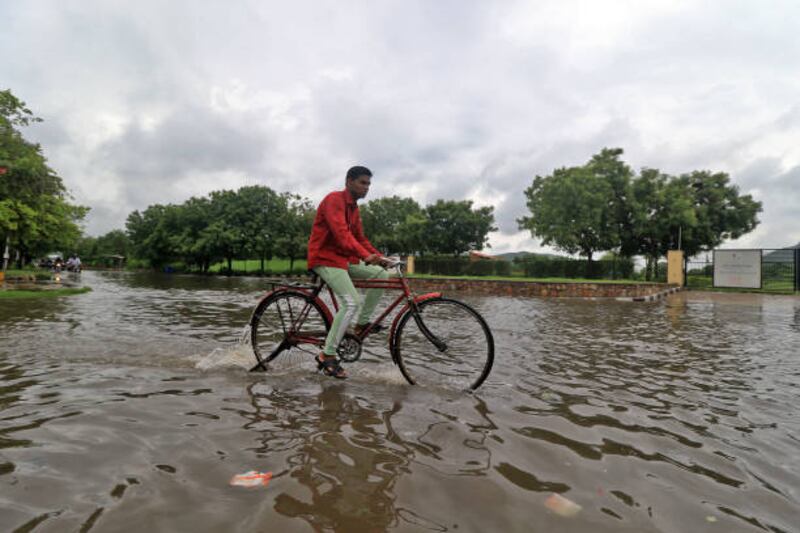 A man cycles through a waterlogged street during monsoon season in Jaipur, Rajasthan, India.