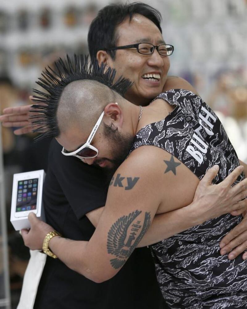 Ken Miyauchi, left, vice president of Softbank, Japanese mobile phone company hugs the first customer to buy an iPhone 6. Shizuo Kambayashi / AP Photo