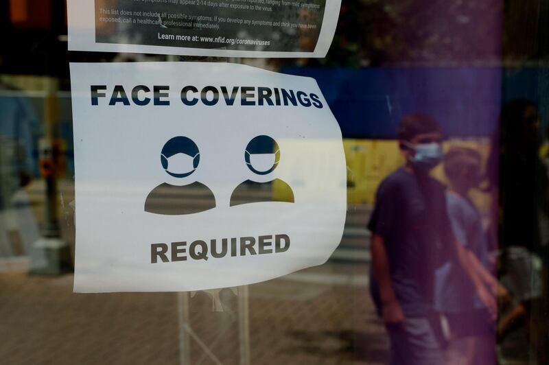 A visitor wearing a masks to protect against the spread of COVID-19 passes a sign requiring masks, Tuesday, July 7, 2020, in San Antonio. Texas Gov. Greg Abbott has declared masks or face coverings must be worn in public across most of the state as local officials across the state say their hospitals are becoming increasingly stretched and are in danger of becoming overrun as cases of the coronavirus surge. (AP Photo/Eric Gay)