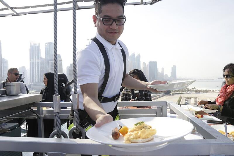 Ritz Carlton JBR catering staffer Jaycee Sumile hands a plate over to one of the 22 guests during the brunch Dinner in th Sky service. Jeffrey E Biteng / The National