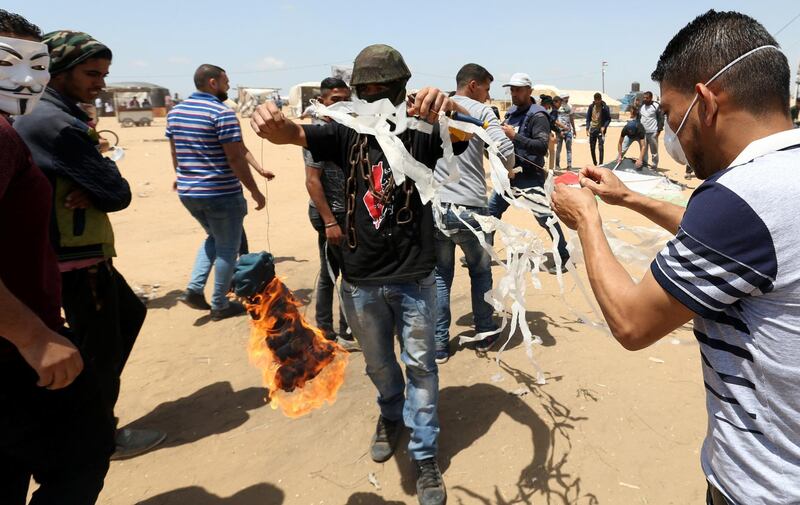 Palestinian demonstrators prepare to set a kite on fire.  Ibraheem Abu Mustafa / Reuters
