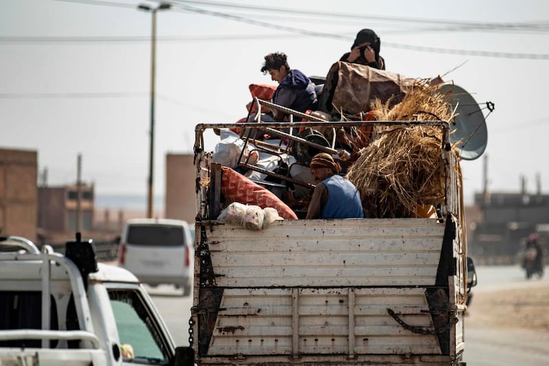 Displaced Syrians sit in the back of a pick up truck as Arab and Kurdish civilians flee amid Turkey's military assault on Kurdish-controlled areas in northeastern Syria in the Syrian border town of Tal Abyad. AFP