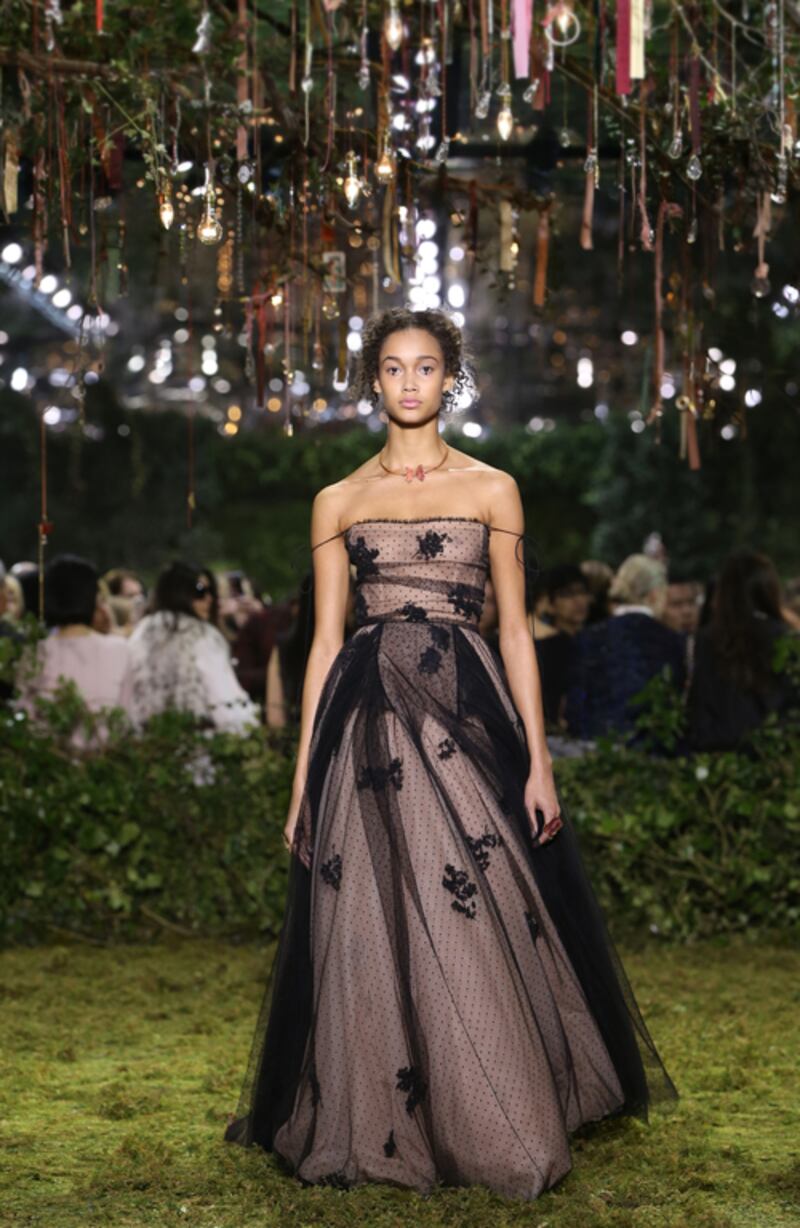 Maria Grazia Chiuri presented her first haute couture collection for Christian Dior in the gardens of the Musee Rodin, and centred her collection around the brand’s iconic Bar jacket. This saw literal jackets and coats in varying lengths give way to a more pared down approach that focused entirely on the cinched-in waist and classic 1950s silhouette. This came to life in an embroidered tulle dress made from black net and decorated with stylised flowers, laid over nude tulle. The multiple layers of gossamer tulle created volume and airiness, while thin ties, carelessly slipped off shoulders, added to the simplicity of the overall look. Courtesy of Christian Dior