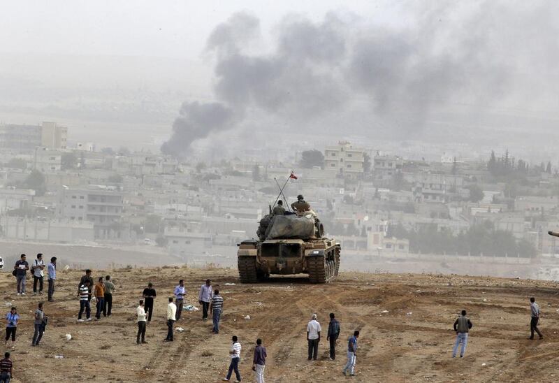 Civilians and Turkish soldiers watch fighting between Syrian Kurds and ISIL militants overlooking the town of Kobani, Syria on October 11, 2014. Lefteris Pitarakis/AP