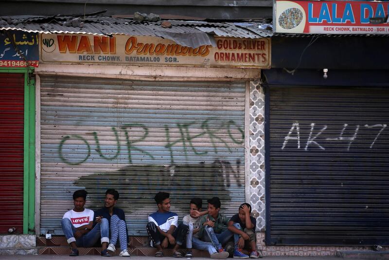 Kashmir boys sit in front of closed shops during restrictions in Srinagar.  Reuters