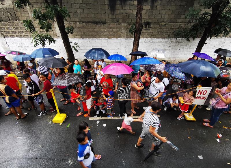 Residents holding umbrellas queue during a gift giving event on Christmas day in Las Pinas city, Philippines.  EPA