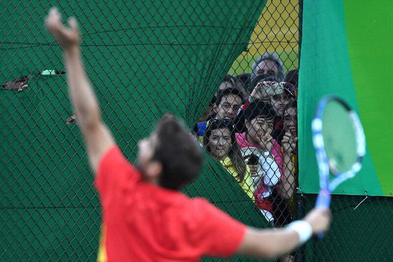 People peer into the tennis court where Spain’s Rafael Nadal and Spain’s Marc Lopez are playing against Canada’s Vasek Pospisil and Canada’s Daniel Nestor during their men’s doubles semi-final tennis match at the Olympic Tennis Centre of the Rio 2016 Olympic Games in Rio de Janeiro on August 11, 2016. Luis Acosta / AFP