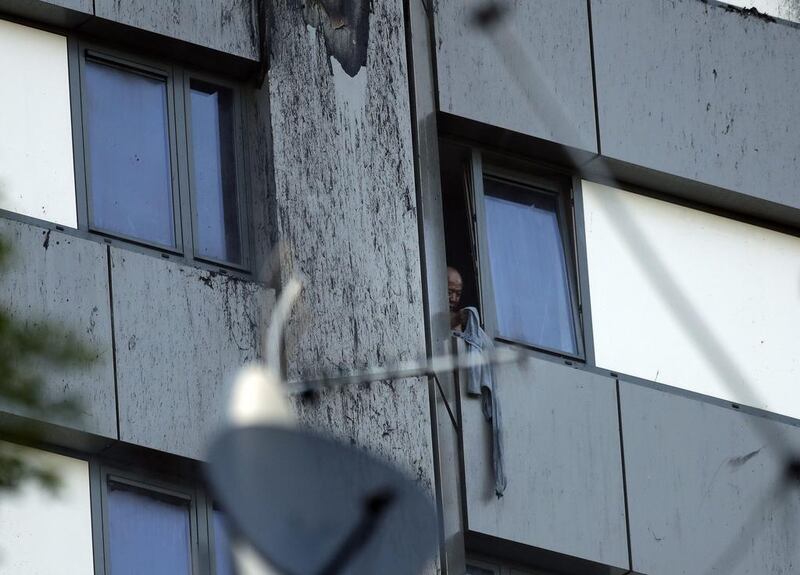 A person peers out of a window from a building on fire in London on June 14, 2017. Matt Dunham / AP Photo