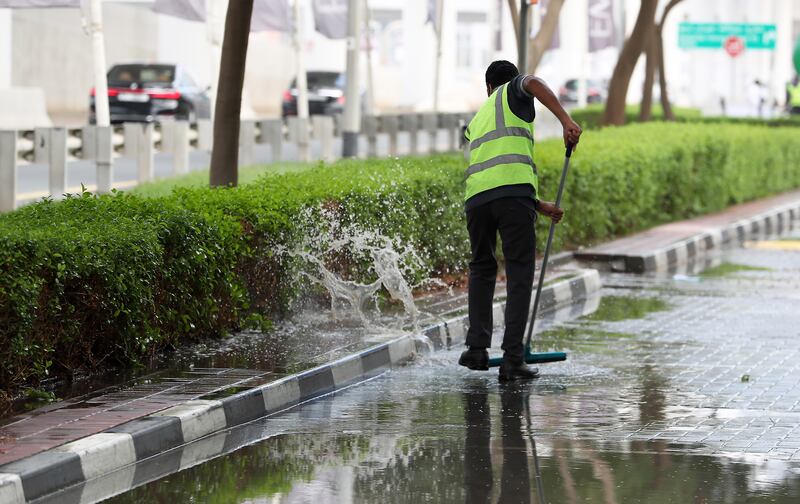 A worker clearing water from a road in the Greens area of Dubai. Pawan Singh / The National