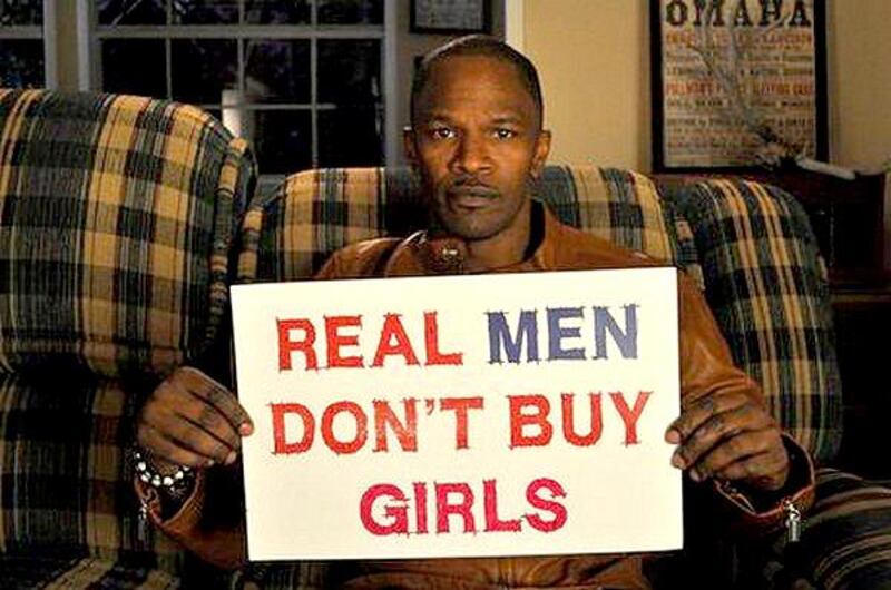 Jamie Foxx holds up a Real Men Don’t Buy Girls sign. Courtesy Jamie Foxx