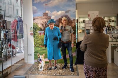 WINDSOR, ENGLAND - MAY 18: A man has his photograph taken next to a life-size cardboard cutout of Queen Elizabeth II displayed in a shop on May 18, 2022 in Windsor, England. The Platinum Jubilee of Elizabeth II is being celebrated from June 2 to June 4, 2022, in the UK and Commonwealth to mark the 70th anniversary of the accession of Queen Elizabeth II on 6 February 1952.  (Photo by Carl Court / Getty Images)