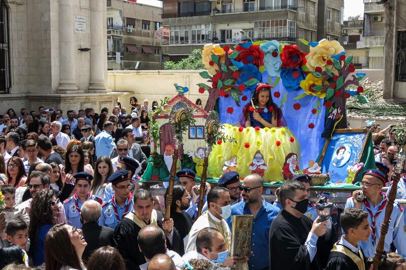 Boy scouts carry a float with a girl dressed as Disney character Snow White during a procession for Palm Sunday at the Greek Orthodox Church of the Holy Cross in the Qasaa district of the Syrian capital Damascus. AFP