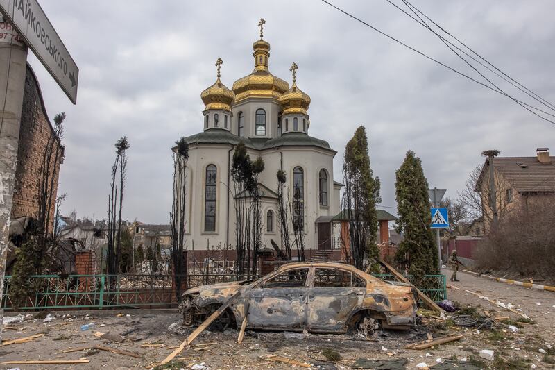 A Ukrainian soldier stands guard next to a church in Irpin. EPA