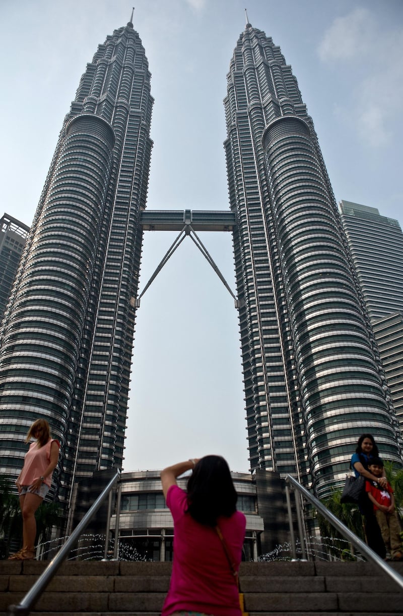 To go with Ukraine-Russia-crisis-aviation-Malaysia-tourism,FOCUS by Bhavan Jaipragas
Tourists pose at the Petronas Twin Towers in Kuala Lumpur on July 23, 2014. An unprecedented second major aviation disaster in four months could further associate Malaysia with calamity in the eyes of travellers, observers warn, putting the tropical destination's vital tourism sector at risk. AFP PHOTO/ MANAN VATSYAYANA (Photo by MANAN VATSYAYANA / AFP)