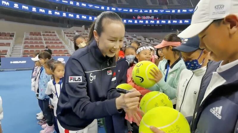 Chinese tennis player Peng Shuai signs large-sized tennis balls at the opening ceremony of Fila Kids Junior Tennis Challenger Final in Beijing, China November 21, 2021, in this screen grab obtained from a social media video. AFP
