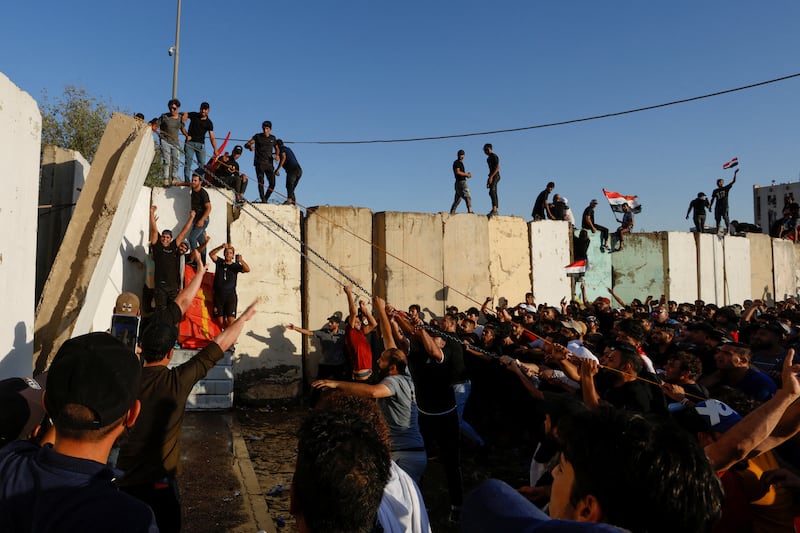 Protesters pull down a wall with chains and ropes during a protest against corruption. Reuters