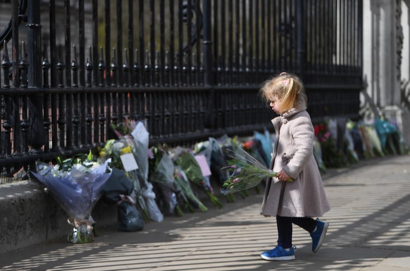 A young girl places flowers outside Buckingham Palace. EPA