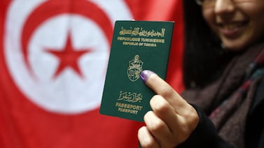 A Tunisian woman shows her passeport and her inked finger  in the Tunisian consulate in Paris on October 24, 2014, after early voting in Tunisia's parliamentary elections, taking place on October 26, 2014. Tens of thousands of soldiers and police will be deployed for October 26's parliamentary polls -- the first since an uprising three years ago that inspired the Arab Spring revolutions. A raid by Tunisian security forces on an armed group near the capital on October 26 left six suspected militants dead, including five women, fanning tensions days ahead of the landmark election.      AFP PHOTO / THOMAS SAMSON (Photo by THOMAS SAMSON / AFP)