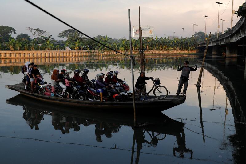 Motorists are being transported on a raft as they cross a river in Jakarta, Indonesia. Reuters