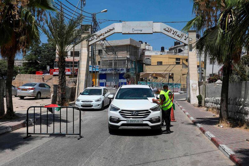 Palestinian volunteers check the temperature of a people in a car at the entrance of the Amari refugee camp near the West Bank city of Ramallah.  AFP