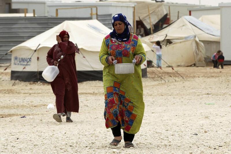 A Syrian woman refugee carries a pot of cooked food at the Zaatari refugee camp in the Jordanian city of Mafraq, near the border with Syria. Muhammad Hamed / Reuters / March 8, 2014