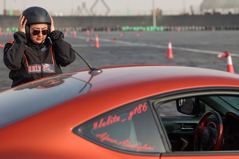 Afnan Almarglani, the first Saudi woman to be certified as an autocross instructor, adjusts her helmet next to her car at Derab circuit, in Riyadh.  AFP