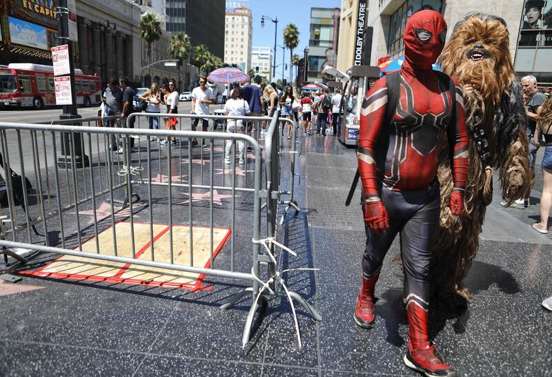 (FILES) In this file photo taken on August 07, 2018, Spider-Man and Chewbacca impersonators walk past a barricade surrounding the location of the vandalized Hollywood star of  US President Donald Trump along the Hollywood Walk of Fame in Hollywood, California. - A US man accused of taking a pickaxe to President Donald Trump's star on the Hollywood Walk of Fame justified his actions on Wednesday, August 15, 2018 as he pleaded not guilty to a felony vandalism charge. "I don't personally think there should be any charges brought against me because what I did, I believe, was a rightful and just act, and I think that the repercussions of it were only positive," Austin Mikel Clay, 24, told ABC7 after appearing in court in Los Angeles.  Clay, who faces three years in prison if convicted, smashed Trump's star in Hollywood on July 25, 2018 and then reportedly called police and told them "see you soon" before leaving the scene. He later turned himself in to police in Beverly Hills. It was the second time Trump's star had been vandalized in less than two years. (Photo by MARIO TAMA / GETTY IMAGES NORTH AMERICA / AFP)