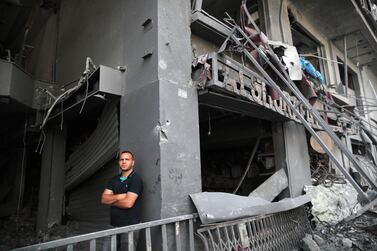A Palestinian man stands next to damaged shops after Israeli air strikes in Gaza city. Reuters