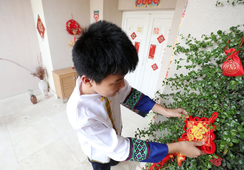 Jeffrey Chen, 12, hangs up decorations for the family celebrations. Chris Whiteoak / The National