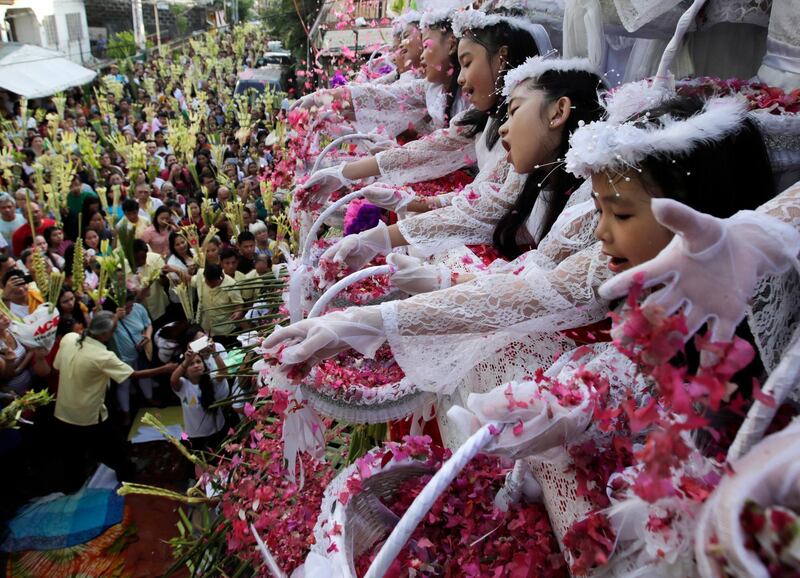 Filipino children shower flower petals onto Catholic devotees holding decorative palm fronds during a procession to mark Palm Sunday in Las Pinas City, south of Manila. EPA