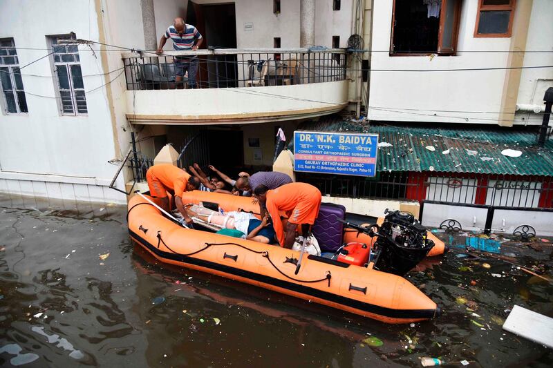 State Disaster Response Force (SDRF) personnel rescue a emn from the flood-affected area of Bahadurpur following heavy rainfalls in Patna in the Indian state of Bihar on September 30, 2019. At least 100 people have died in northern India over the last three days in unusually heavy late monsoon rains which have submerged streets, hospital wards and houses, officials said on September 30. Dozens of boats were pressed into service on streets overflowing with gushing rain water in Patna, the capital of the eastern state of Bihar, after torrential downpours far stronger the normal. / AFP / Sachin KUMAR
