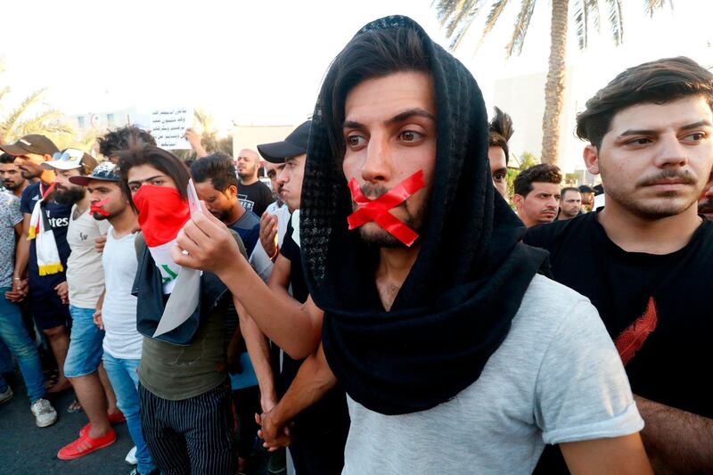 Iraqis with tape on their mouths attend a protest in Basra. AFP