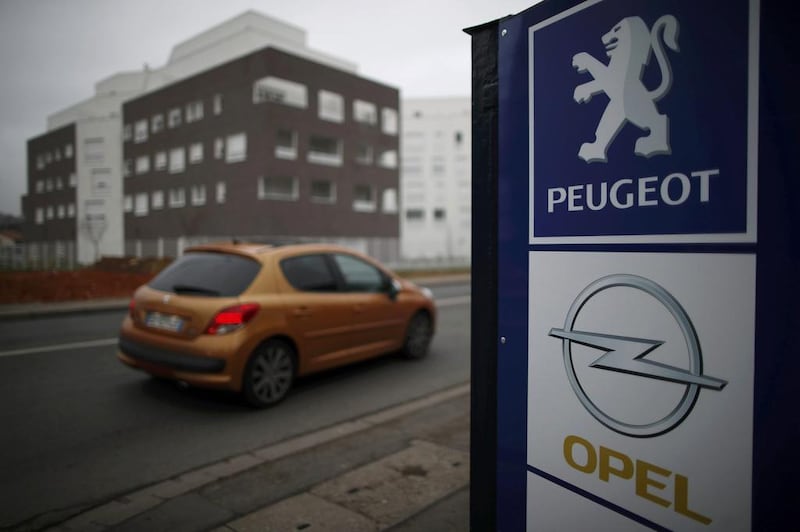 A Peugeot drives past the logos of French car maker Peugeot and German car maker Opel at a dealership in Villepinte, near Paris, France.   RChristian Hartmann / Reuters