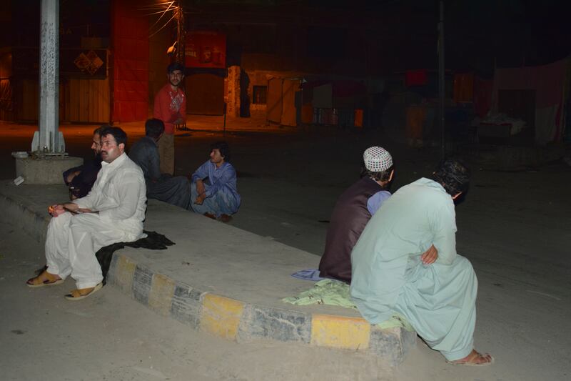 Local residents take refuge outside their houses following the quake. AP