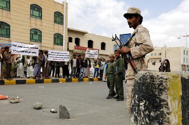 A Yemeni soldier keeps watch as Baha'i faith members hold banners during a protest against the trial of member of Hamed Haydara outside the state security court in Sanaa. EPA