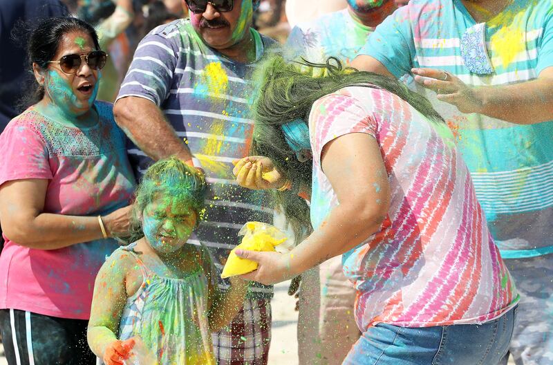 People smear coloured powder on each other at Al Mamzar Beach Park in Dubai. Pawan Singh / The National