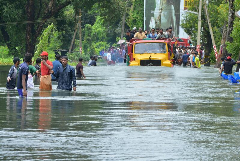 A truck carries people past a flooded road in Thrissur, in the southern Indian state of Kerala, Saturday, Aug. 18, 2018. Rescuers used helicopters and boats on Friday to evacuate thousands of people stranded on their rooftops following unprecedented flooding in the southern Indian state of Kerala that killed hundreds, officials said. (AP Photo)