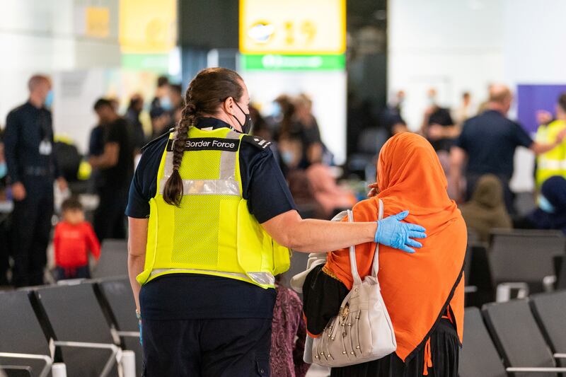 A member of Border Force staff assists a female evacuee as refugees arrive from Afghanistan at Heathrow Airport in August 2021.  Reuters