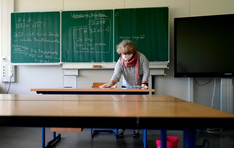 A teacher cleans and disinfects chairs and tables at the the Phoenix Gymnasium secondary school in Dortmund, western Germany. Students preparing for the Abitur high school graduation with exams taking place in May are allowed to turn back to school from April 23, 2020. AFP