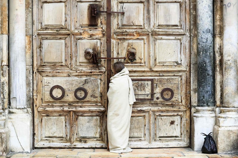 A Christian pilgrim dressed as Jesus Christ stands in front of the closed door of the Holy Sepulchre Church in Jerusalem's Old City. AFP