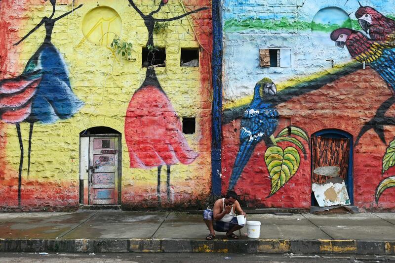 A man washes his face early in the morning outside a warehouse decorated with a wall mural in Mumbai, India. AFP

