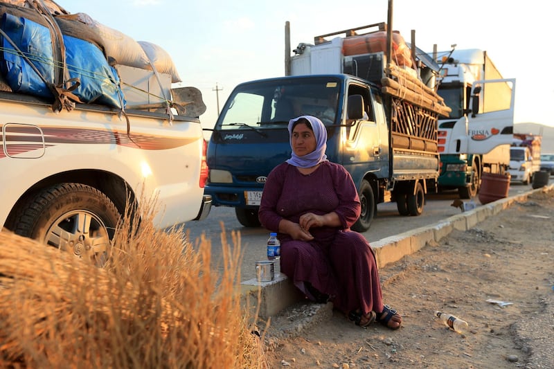 Wife of displaced Yazidi Nayef Al Hamo sits with her neighbours on the road as she heads back to Sinjar following the outbreak of the coronavirus disease and economic crisis, near Dohuk. Reuters, file