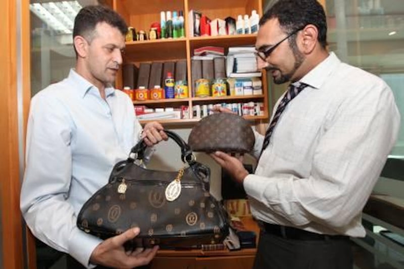 DUBAI - OCTOBER 11,2010 - Mr. Imad Badawi, ( left  ) ,  Director of Intellectual Property Enforcement inspect the fake bags confiscated on a shop that sells fake products with him is Mr Sarmad Manto, (right ) ,Lawyer. ( Paulo Vecina/The National )