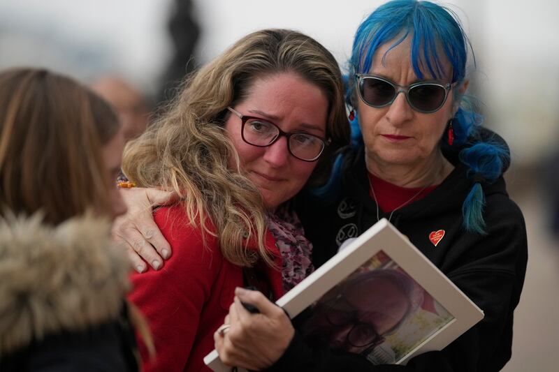 Becca Slater, centre, receives a hug as she remembers her father Anthony Elward, who died in 2020. AP Photo